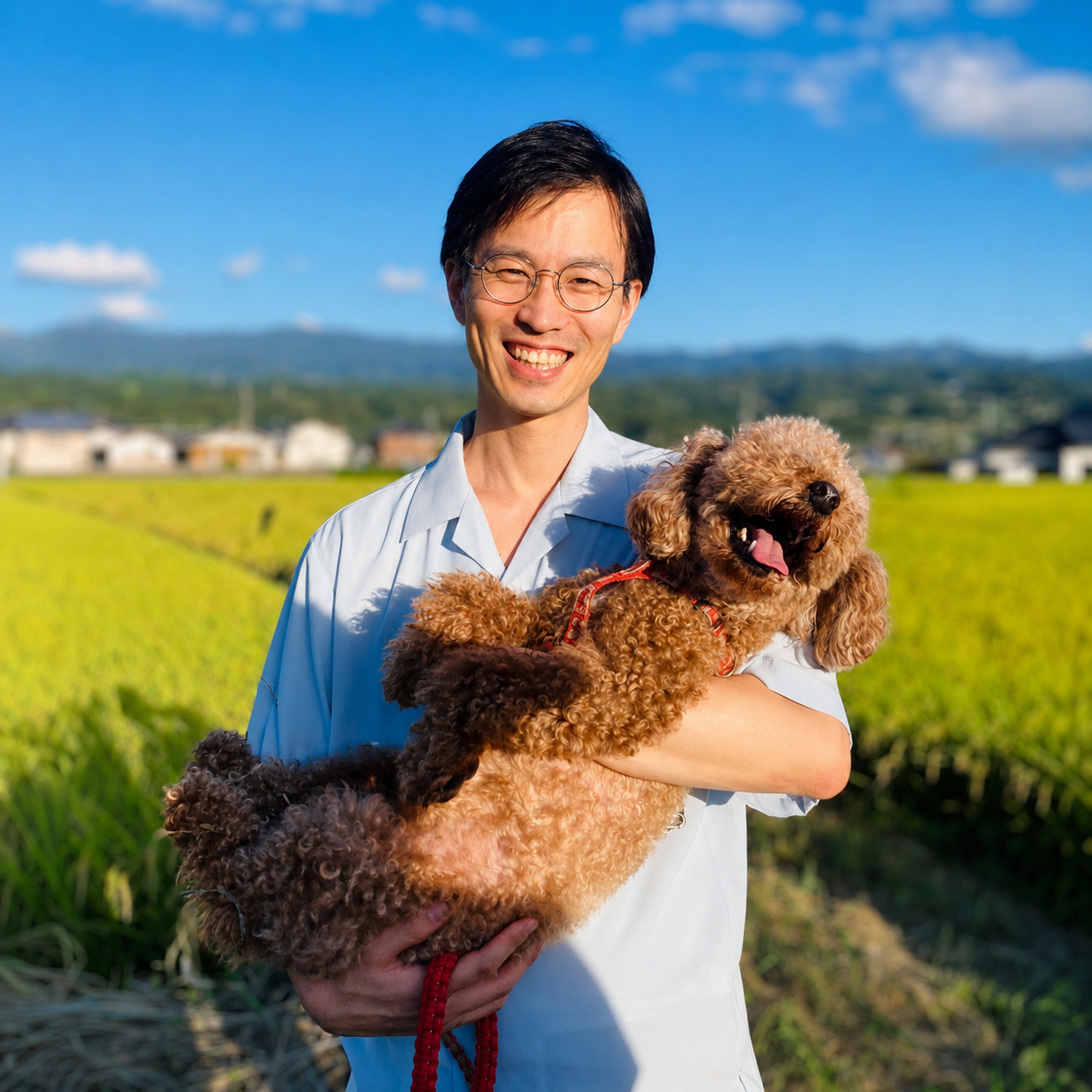 田園風景の中で愛犬を抱いて笑う講師の多田啓二
